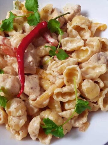 A bowl of creamy fajita pasta, decorated with chili and coriander.