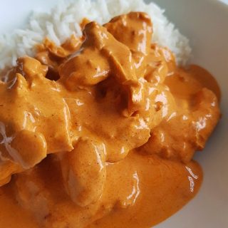 Chicken paprikash with rice on a white plate.