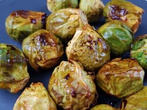 Roasted brussel sprouts with honey and sriracha on a dark plate.