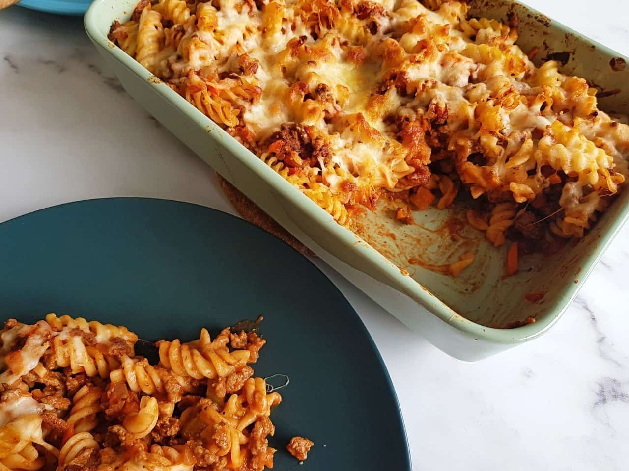 Minced beef pasta bake with a plated portion in front.