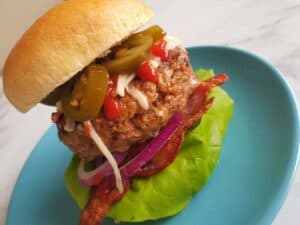 A delicious spicy beef burger on a blue plate.