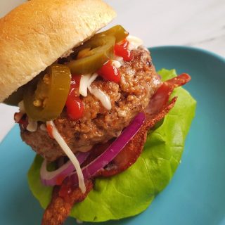 A delicious spicy beef burger on a blue plate.