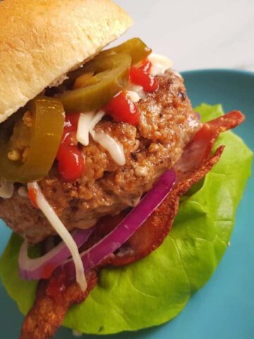 A delicious spicy beef burger on a blue plate.