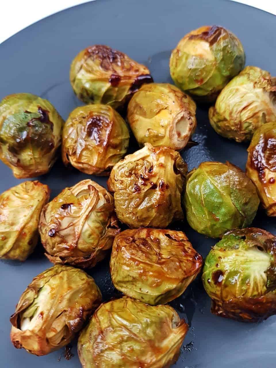 Oven roasted honey and sriracha brussels sprouts on a grey plate.