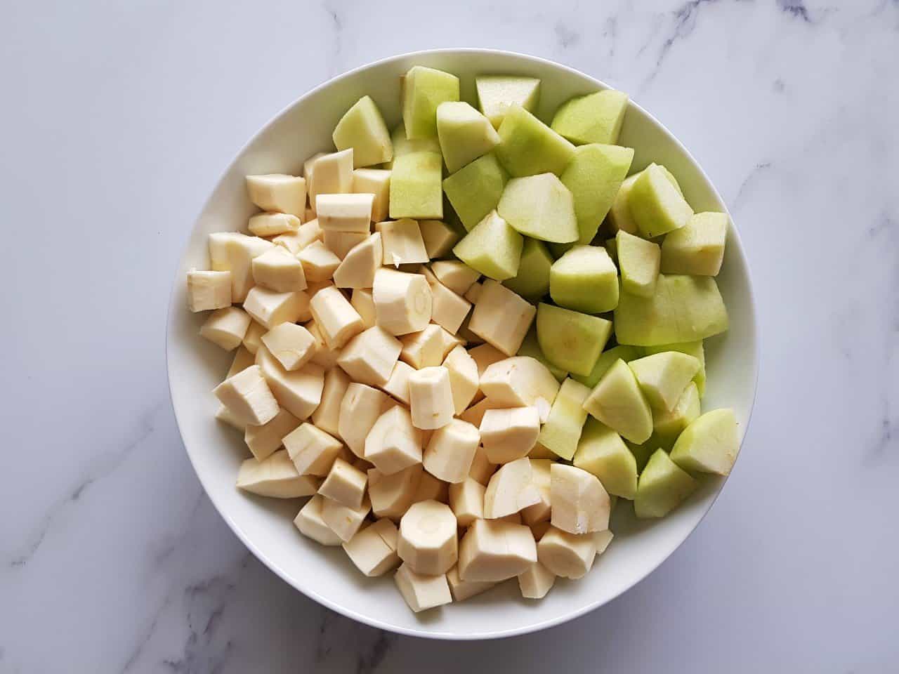 Diced parsnips and apples in a white bowl sat on a table.