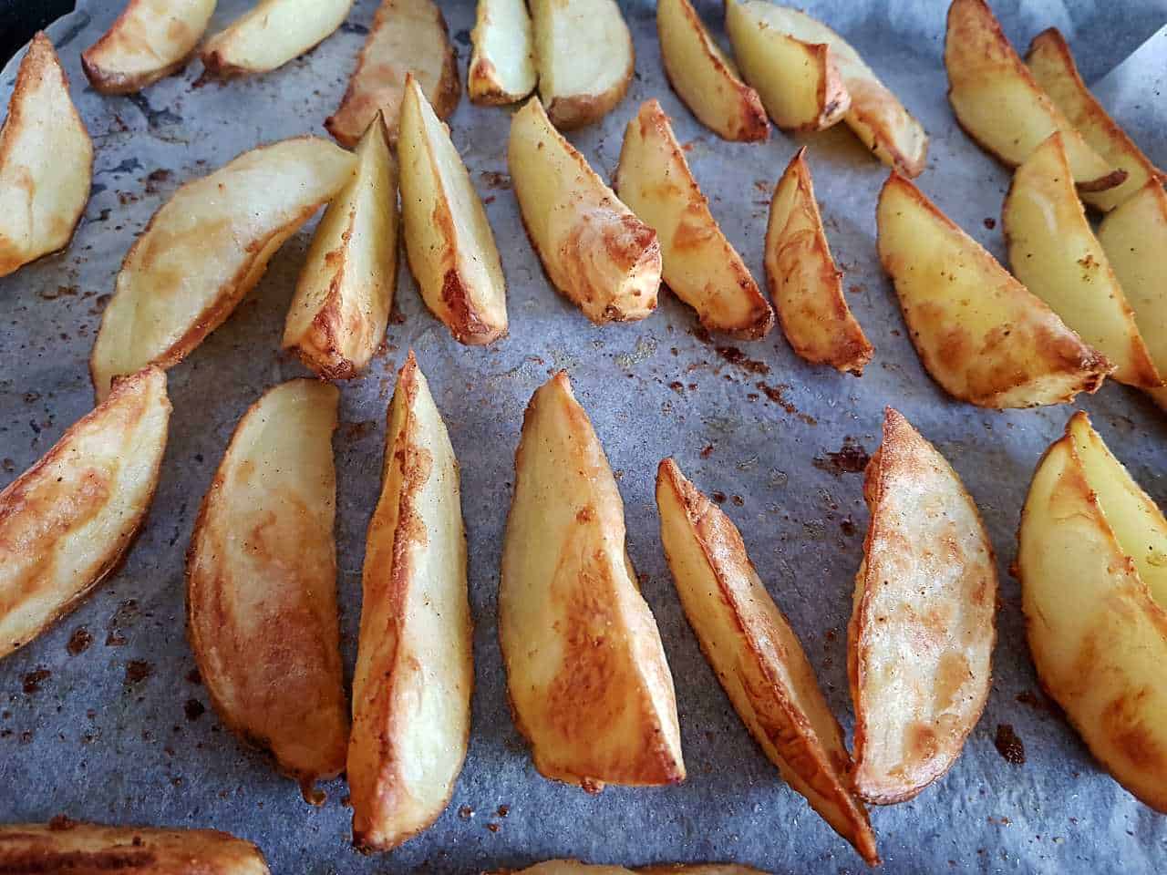 Cooked potato wedges on a baking sheet.