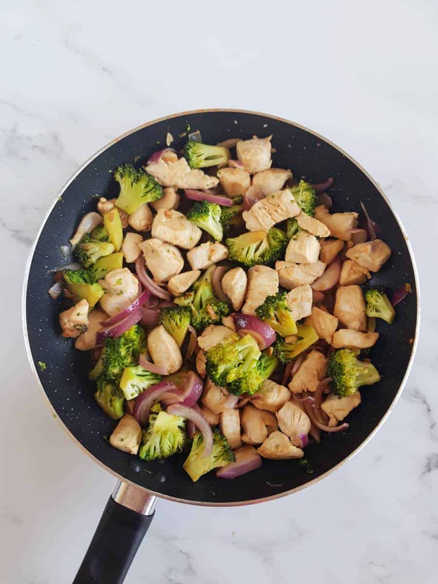 Broccoli and chicken stir fry in a skillet.