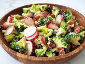 Broccoli salad with raisins and bacon in a wooden bowl.