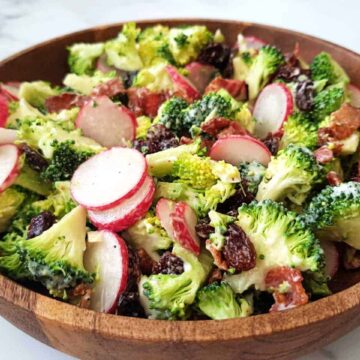 Broccoli salad with raisins and bacon in a wooden bowl.