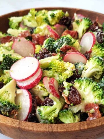 Broccoli salad with raisins and bacon in a wooden bowl.