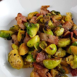 Brussels sprouts and bacon on a white plate.