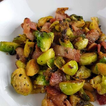 Brussels sprouts and bacon on a white plate.