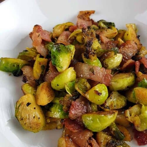 Brussels sprouts and bacon on a white plate.
