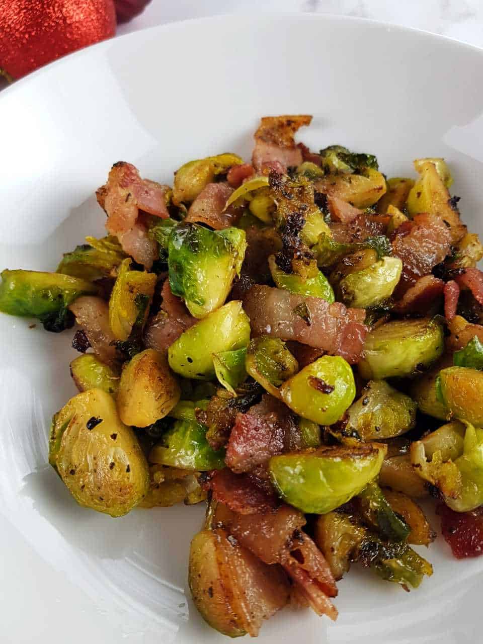 Brussels sprouts and bacon on a white plate.