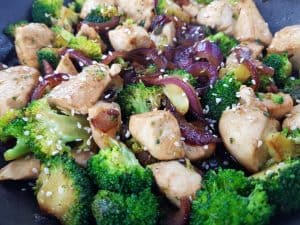 Chicken and broccoli stir fry in a black pan.
