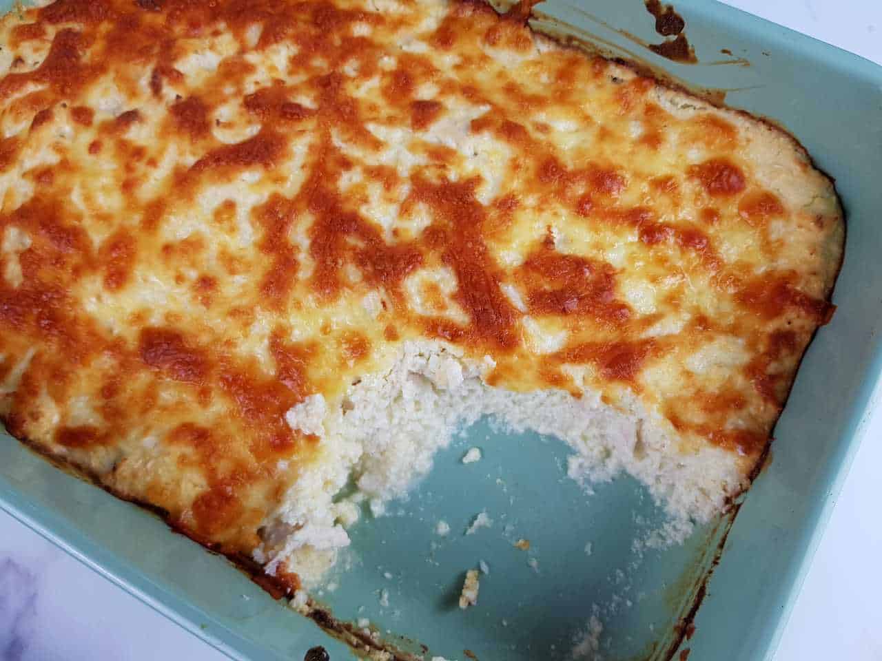 Chicken casserole in a blue casserole dish on a marble table.