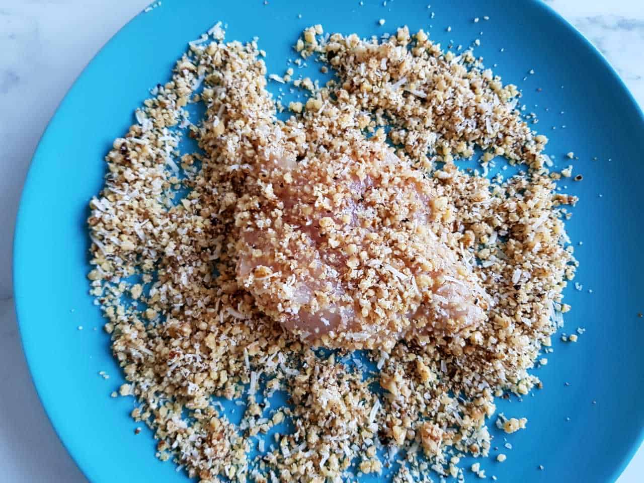 Chicken in walnut crumbs on a blue plate.