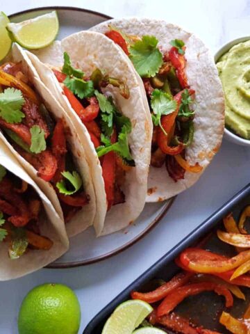 Plated fajitas with guacamole and lime on the side.