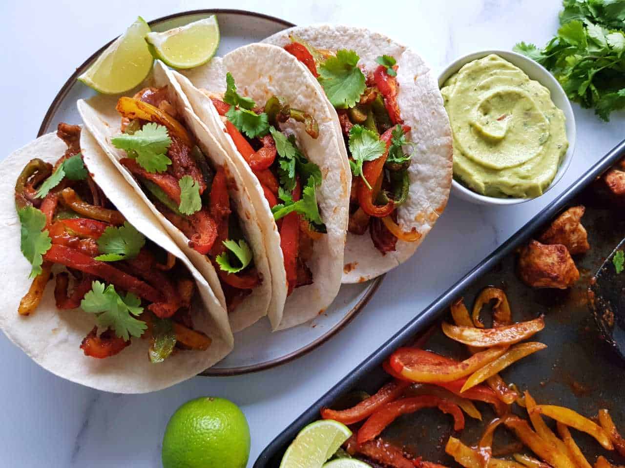 Plated fajitas with guacamole and lime on the side.