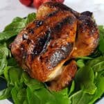 Honey glazed roast chicken on a bed of spinach.