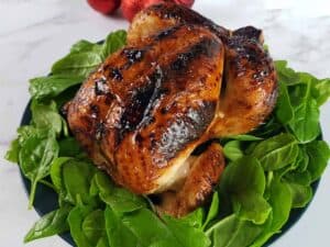 Honey glazed roast chicken on a bed of spinach.