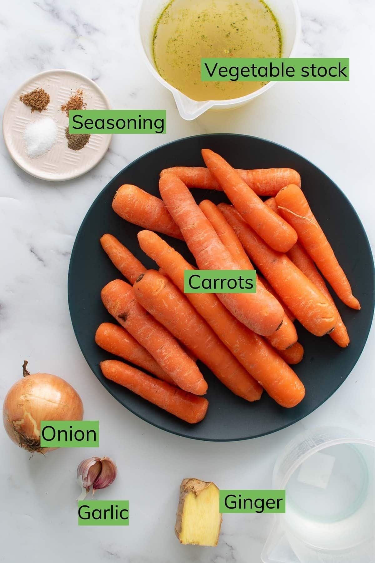 The ingredients needed to make carrot and ginger soup laid out on a table.