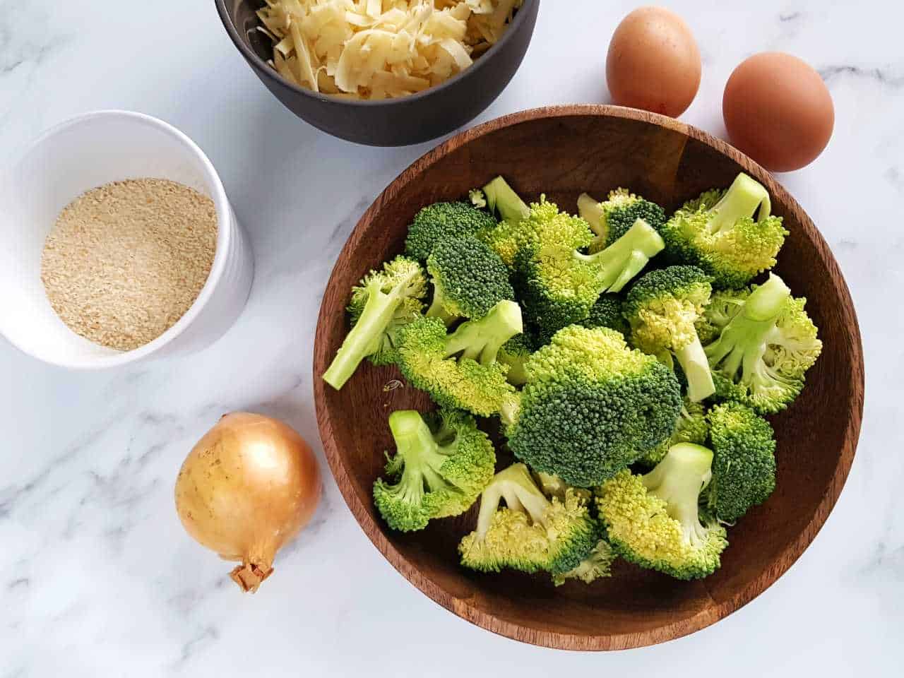 Ingredients for broccoli and cheese balls on a marble table.