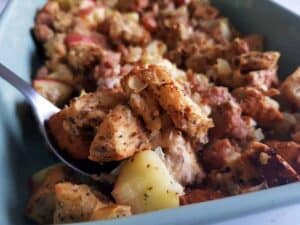 Sausage apple stuffing in a green casserole dish.