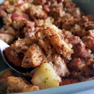 Sausage apple stuffing in a green casserole dish.