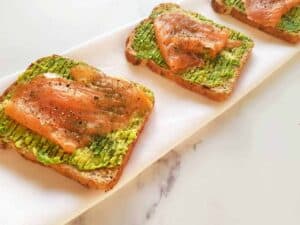 Smoked salmon and avocado toast on a marble table.