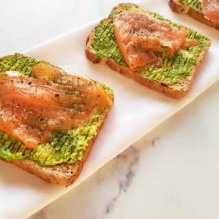 Smoked salmon and avocado toast on a marble table.