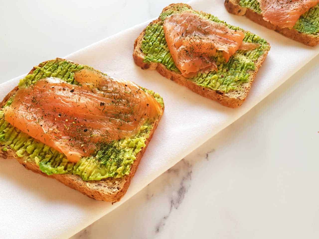 Smoked salmon and avocado toast on a marble table.