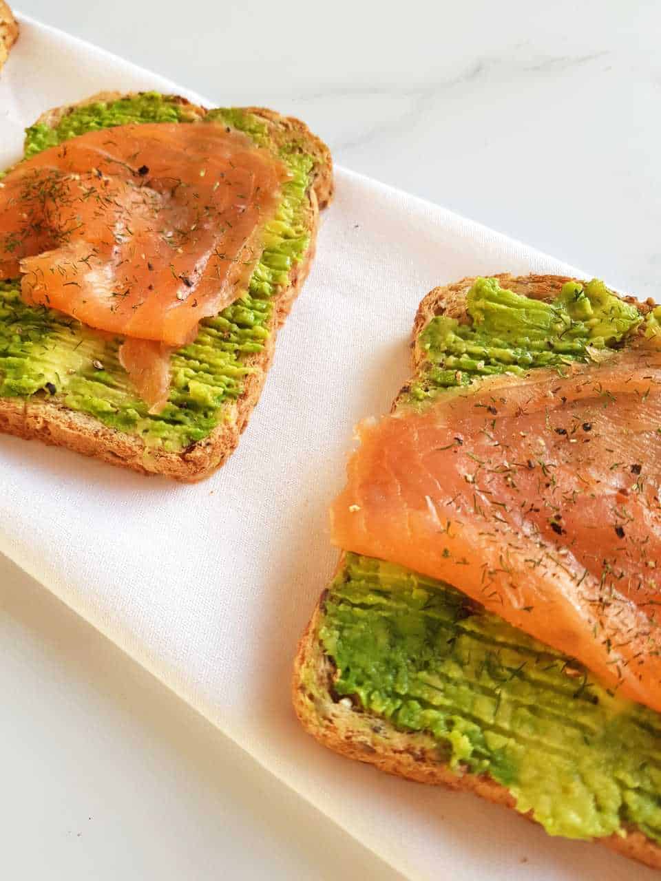 Smoked salmon avocado toast on a marble table.