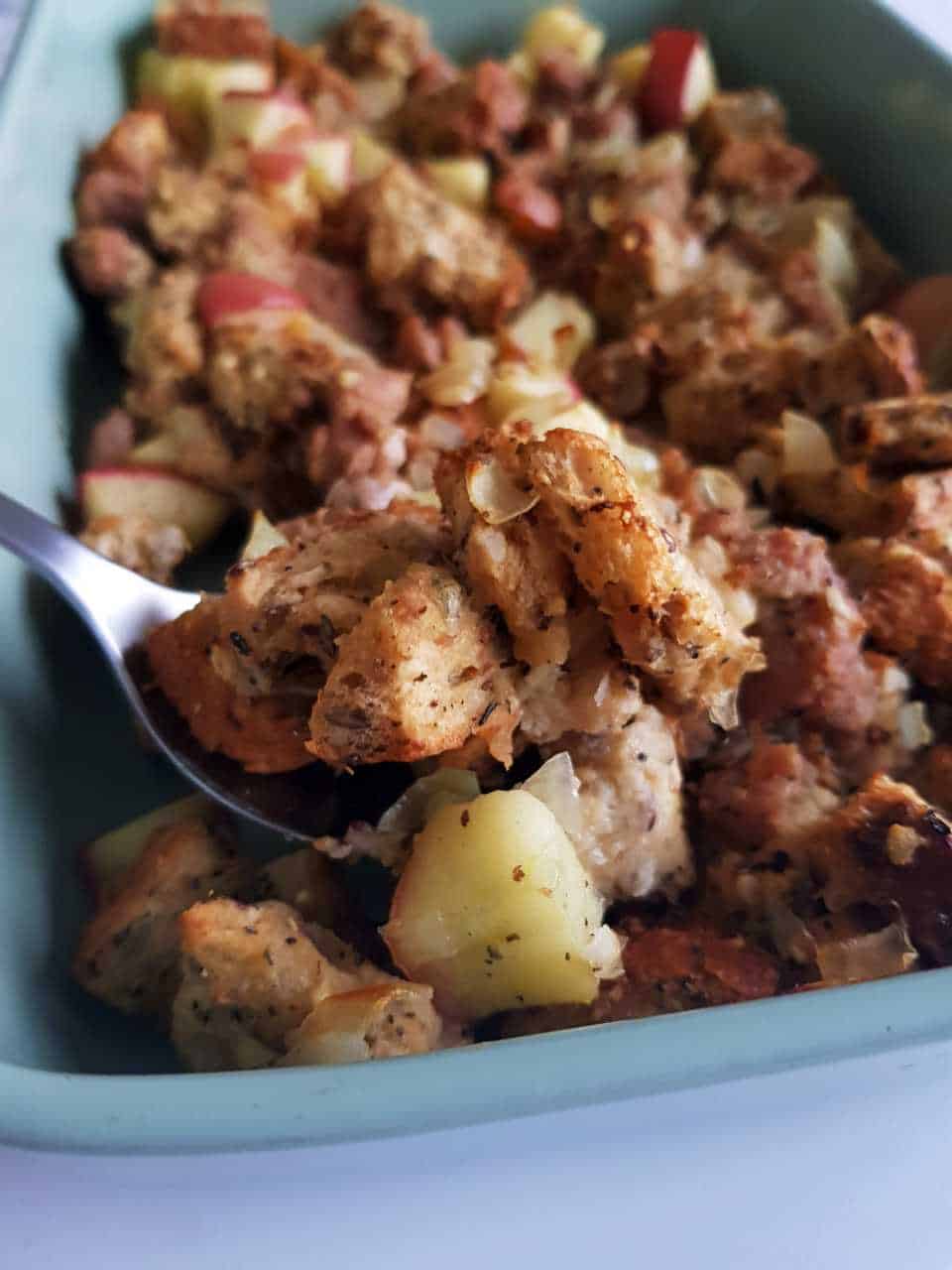 Stuffing with sausage and apples in a green oven dish.