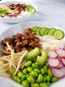 Teriyaki tofu bowls on a marble table.