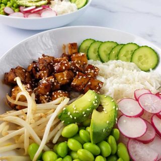 Teriyaki tofu bowls on a marble table.