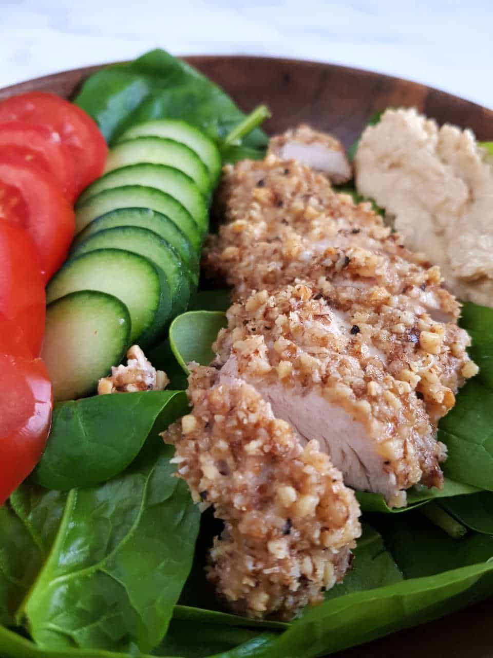 Walnut crusted chicken with a salad in a wooden bowl.