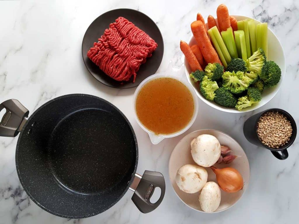 Barley soup ingredients on a marble table.