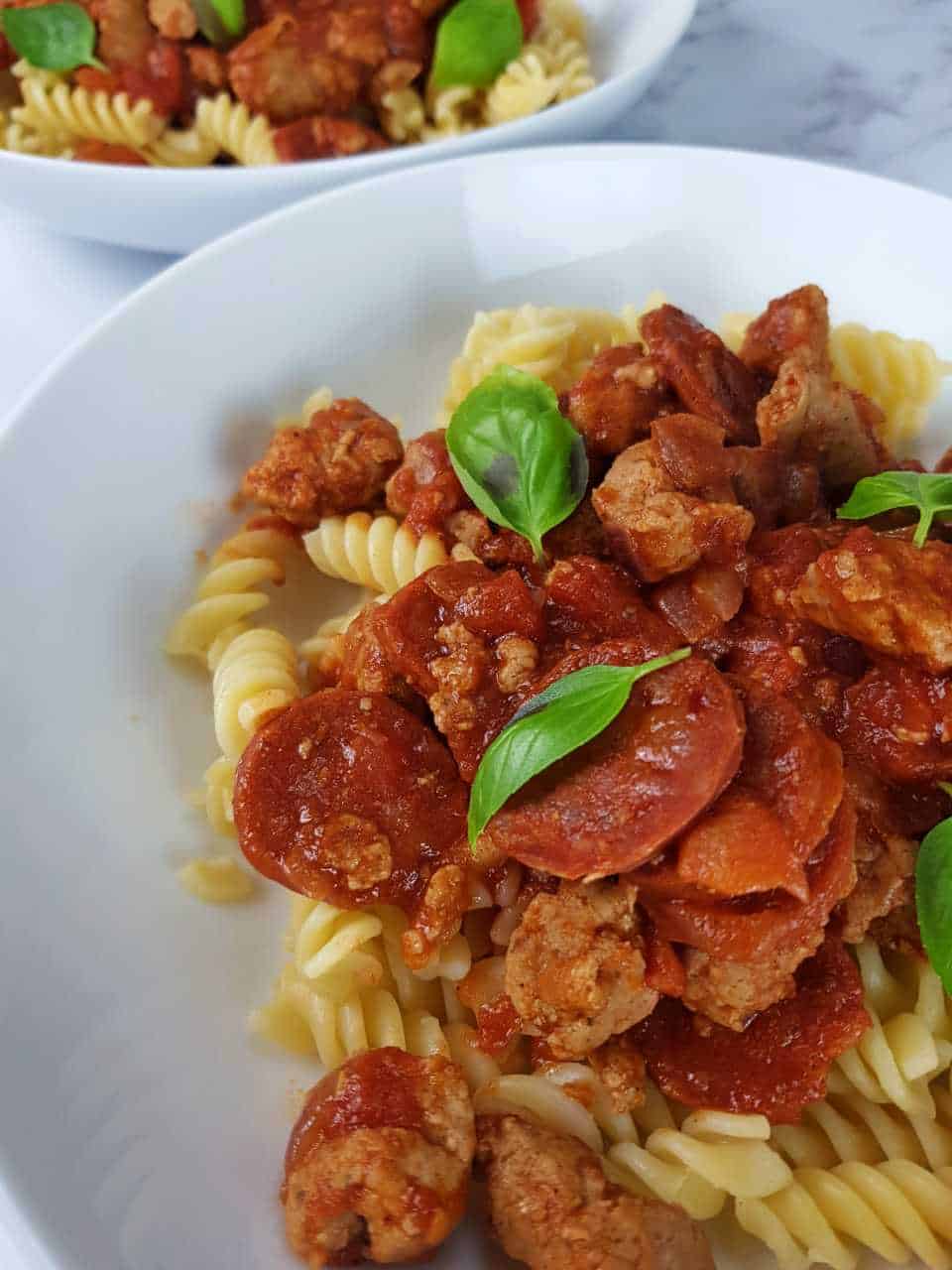 Moroccan sausage pasta with chorizo in white bowls.