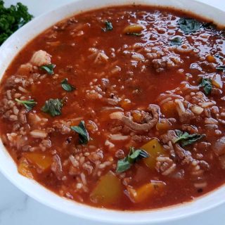 Stuffed pepper soup in a white bowl on a marble table.