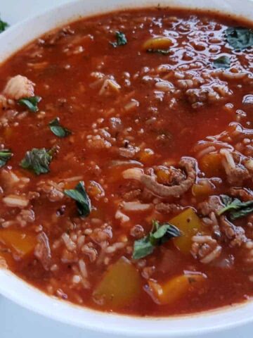 Stuffed pepper soup in a white bowl on a marble table.