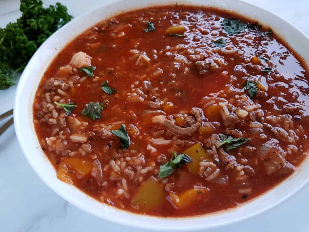 Stuffed pepper soup in a white bowl on a marble table.