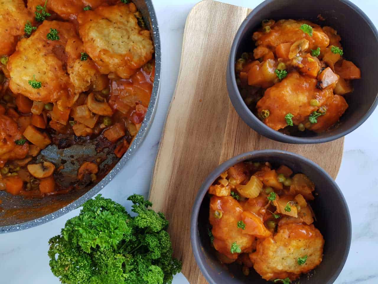 Vegetable stew in gray bowls with a pot of stew on the side.