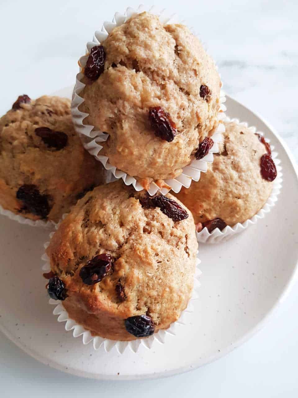 Oat muffins with raisins on a white plate on a marble table.