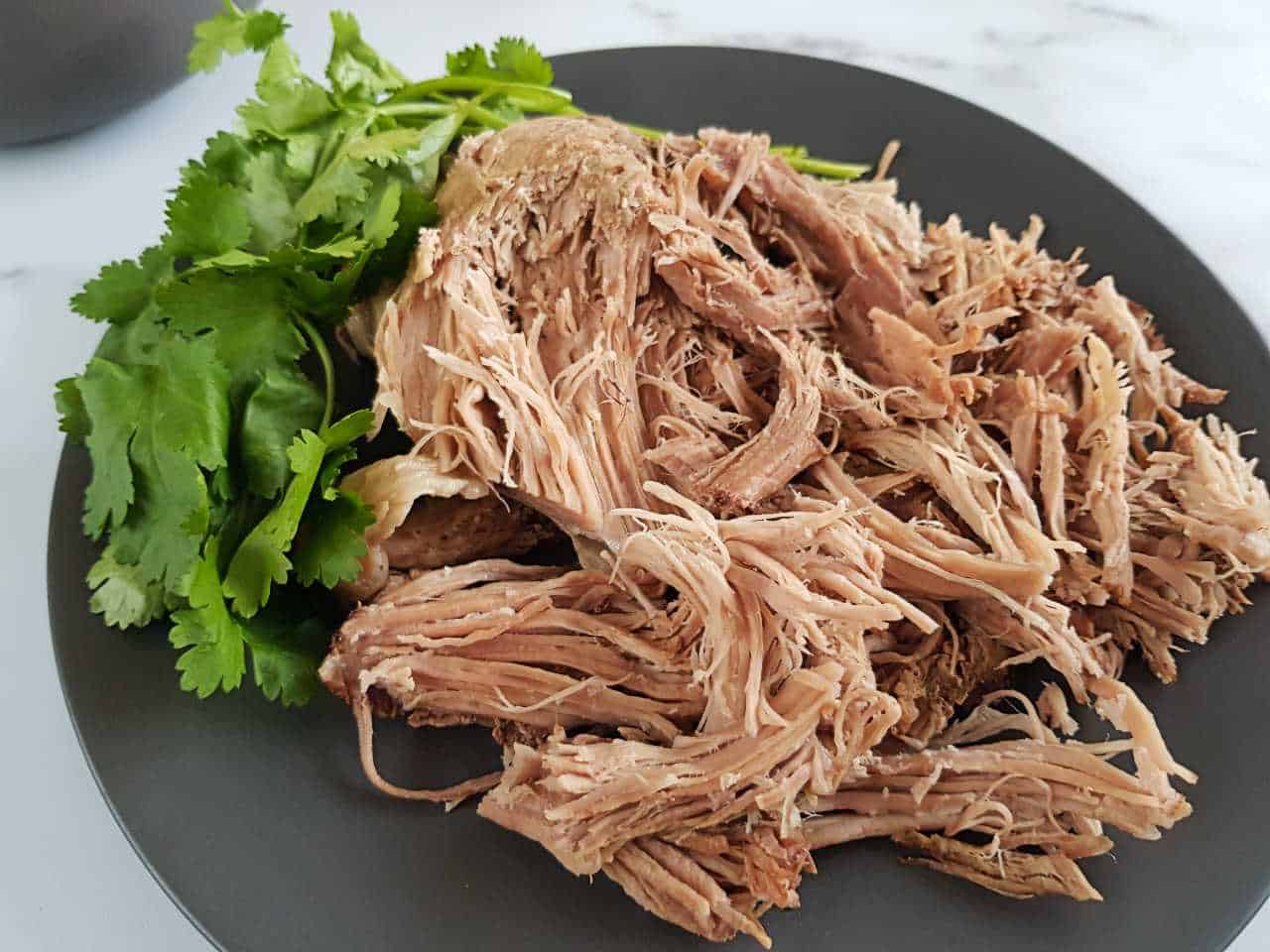 Pulled pork on a gray plate on a marble table.