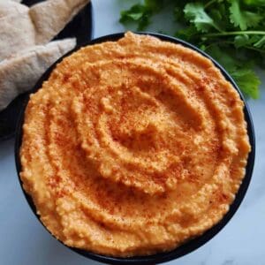 close up of a bowl of red pepper hummus.