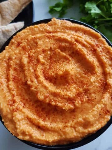 close up of a bowl of red pepper hummus.