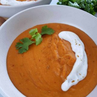 Sweet potato soup in white bowls on a marble table.