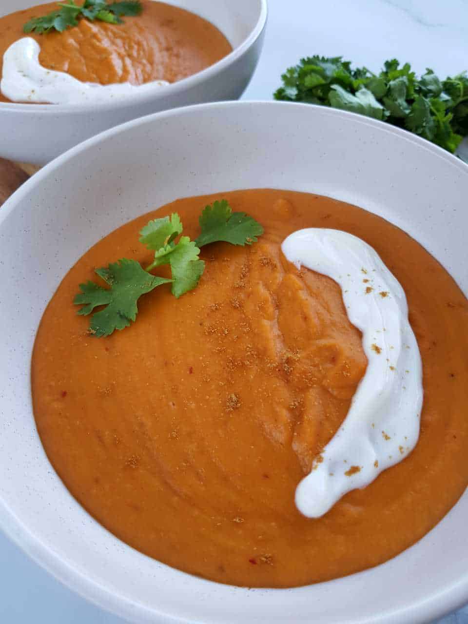 Sweet potato soup in white bowls on a marble table.