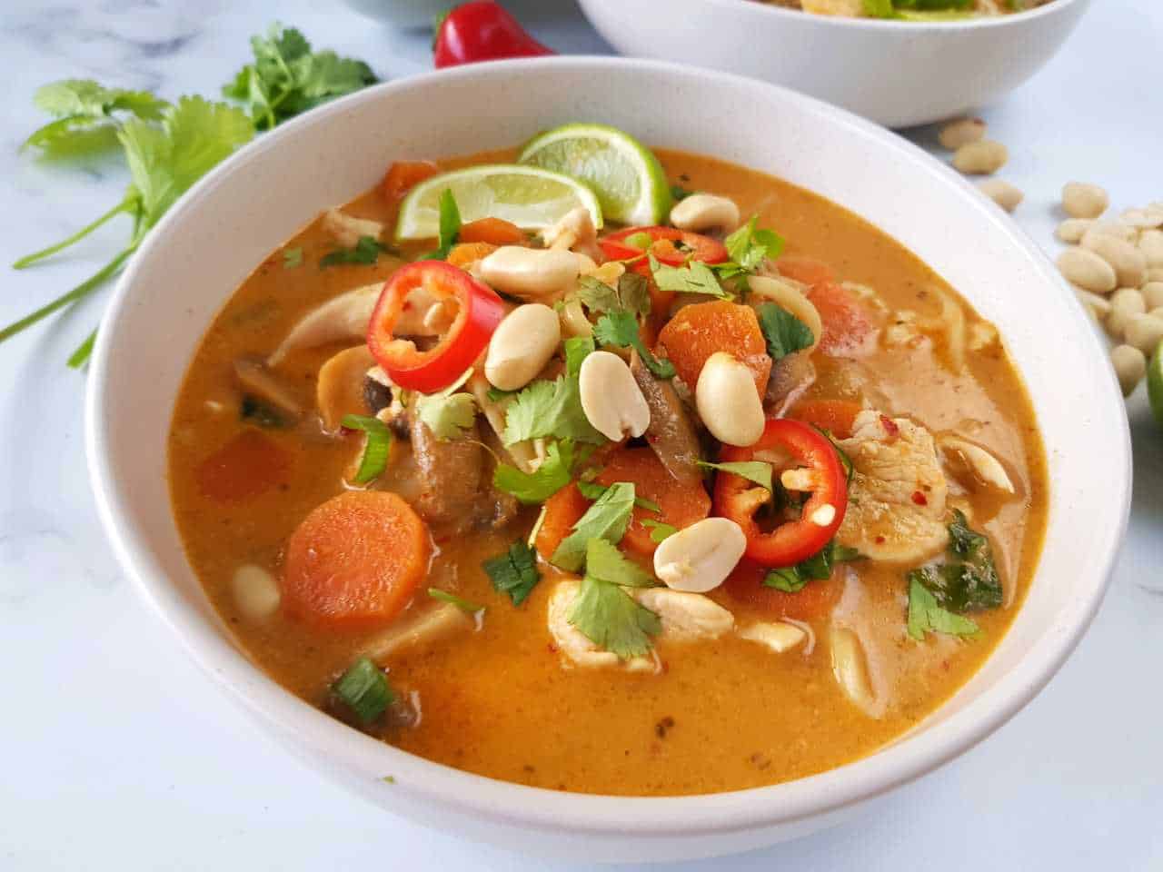 Ramen soup in a white bowl with garnish scattered.